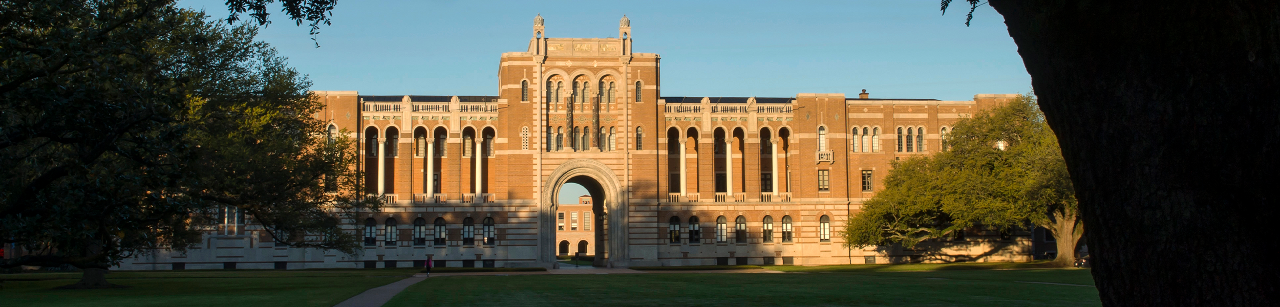 Lovett Hall at Rice University framed by large trees and greenery on campus.